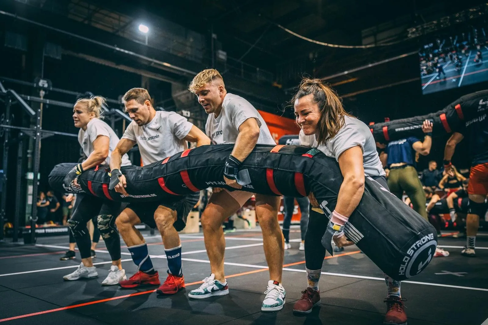 Ein Functional-Fitness-Team trägt gemeinsam einen Sandsack im Wettkampf